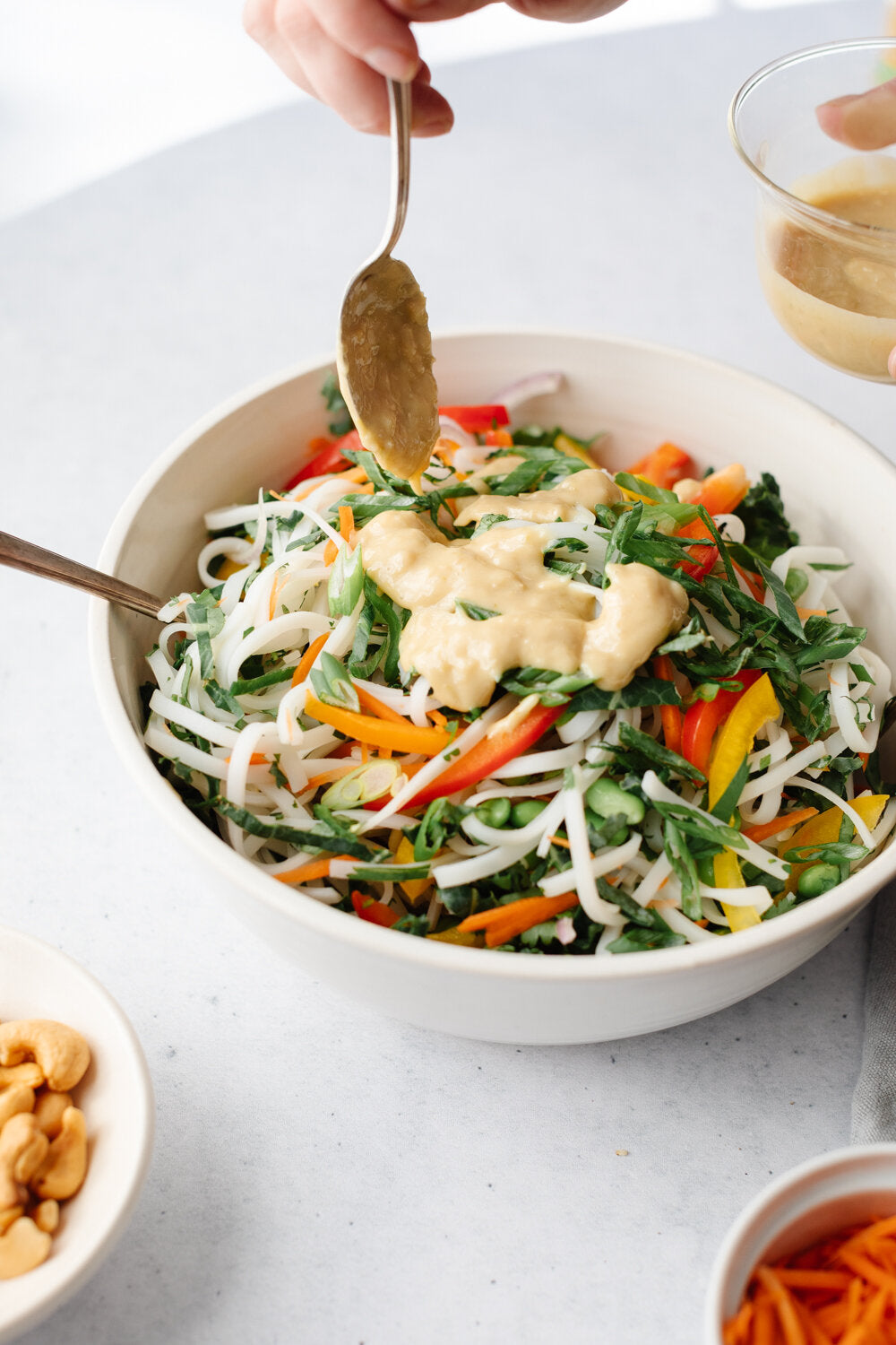 Rainbow Thai Noodle Salad being drizzled with a tahini lime dressing
