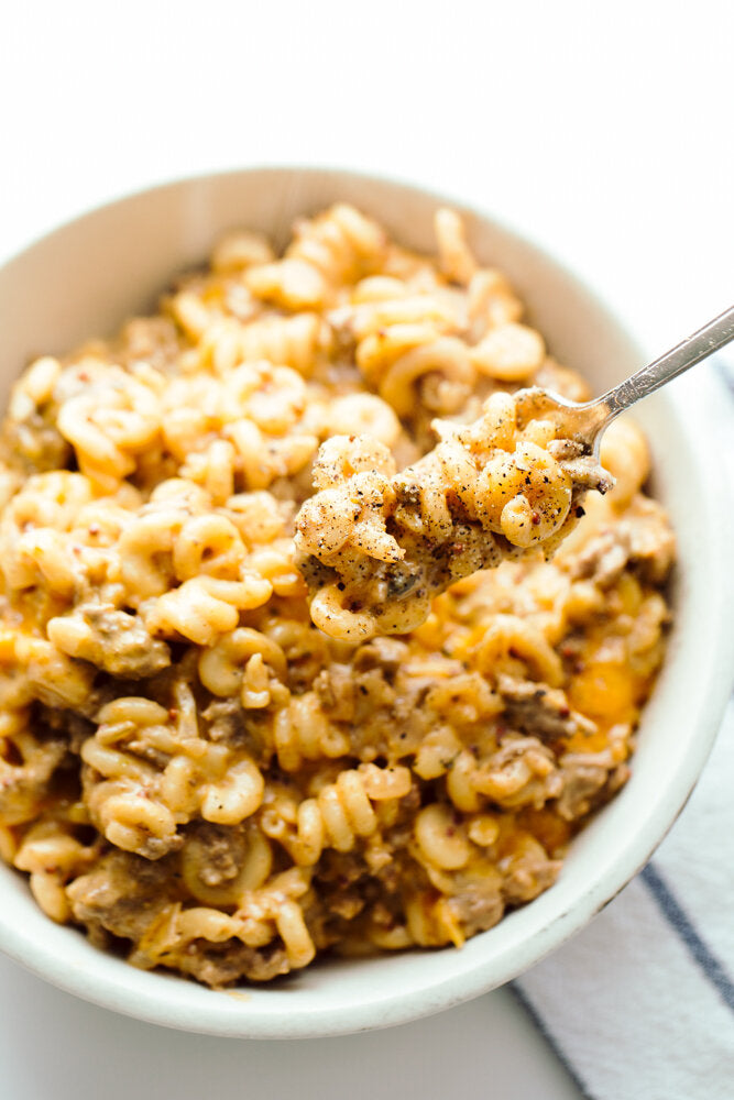 Crock-Pot Cheeseburger Mac n’ Cheese on a fork hovering over a bowl of the Mac n' Cheese