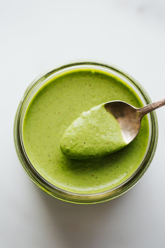 Green Goddess Dressing being spooned out of a glass container