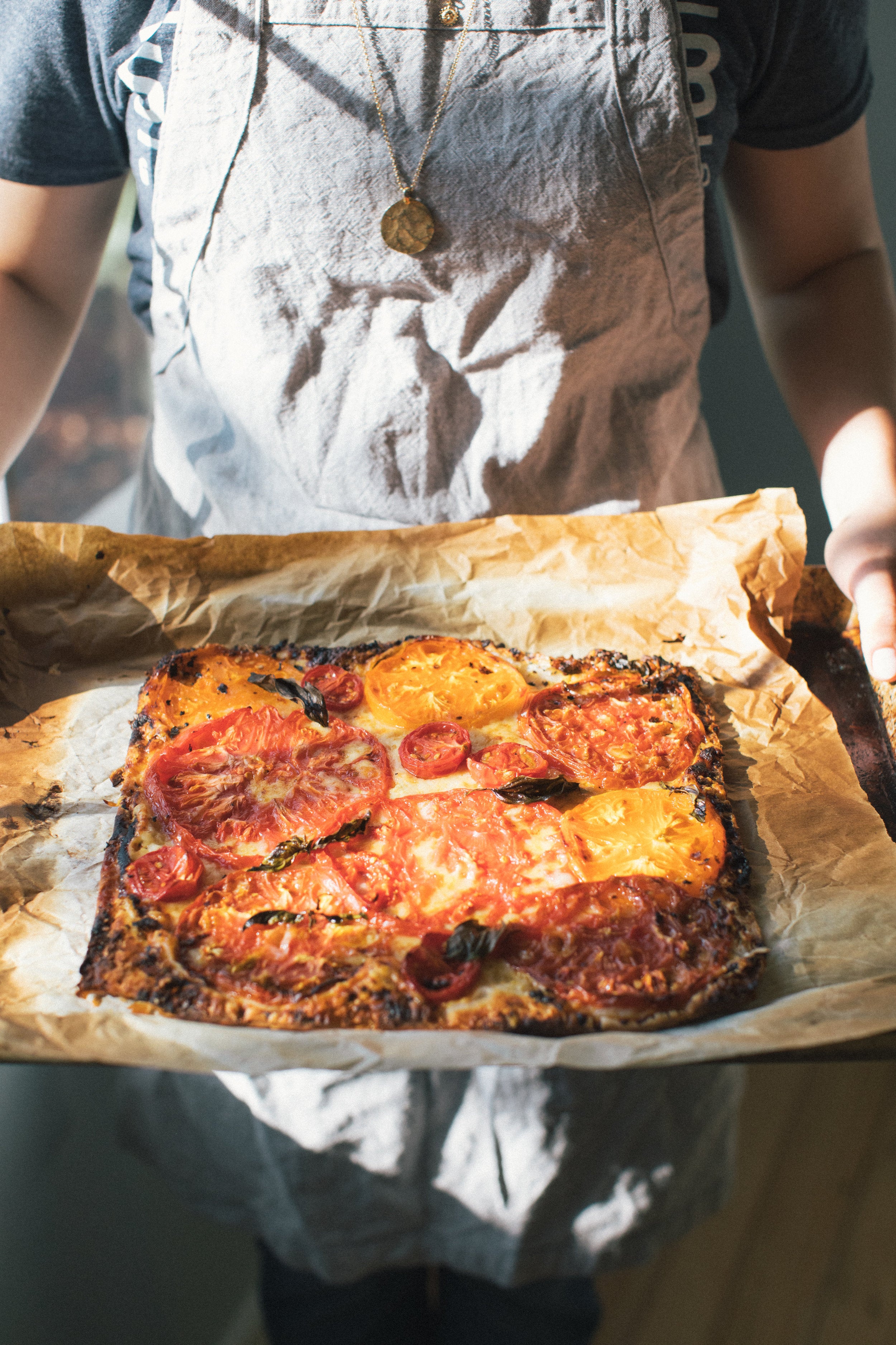 woman holding the tomato dijon tart on parchment paper