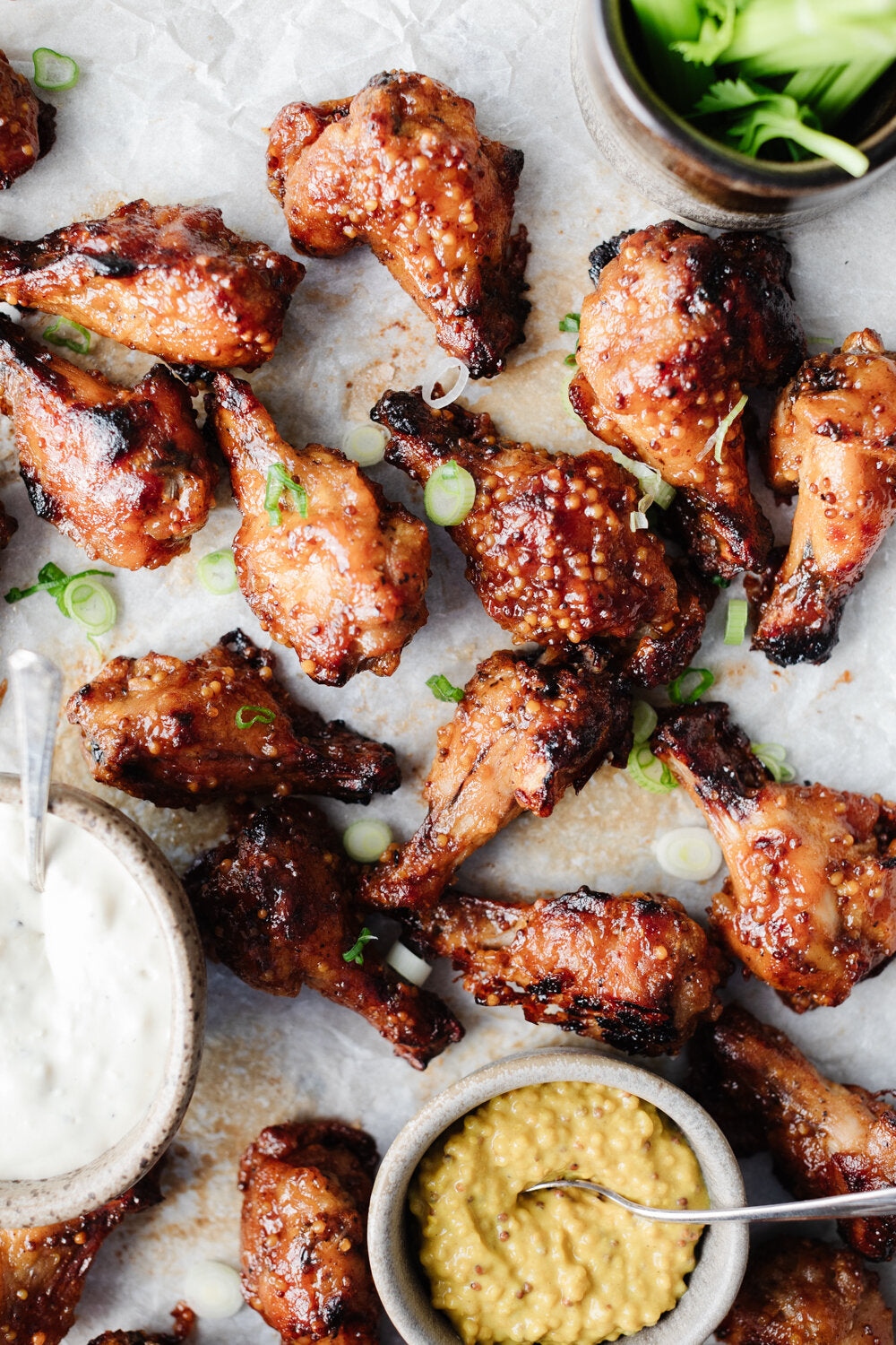 Honey BBQ Wings on parchment with Blue Cheese Tahini Dip and side bowl of grainy mustard