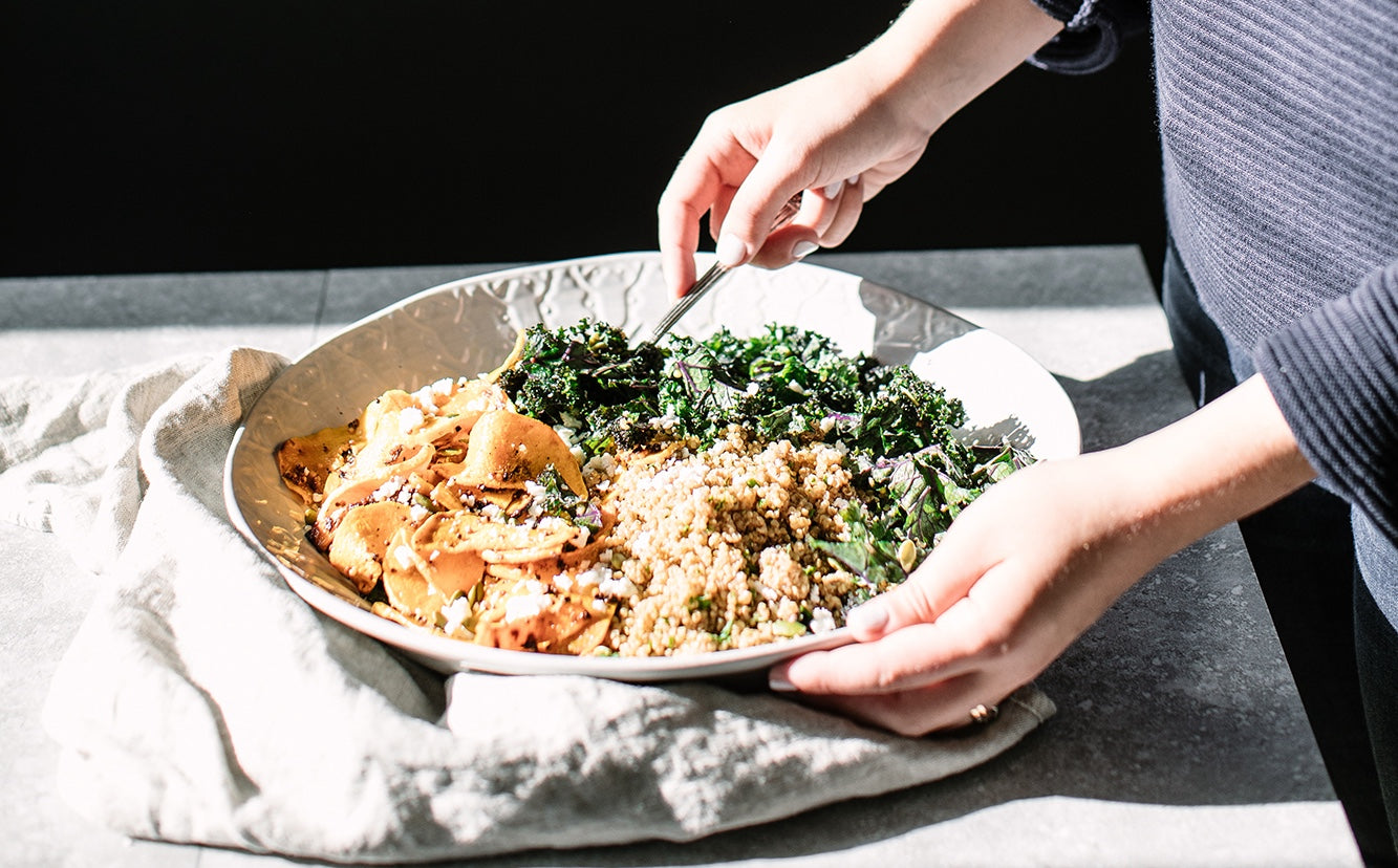 A woman mixing a Squash and Kale Quinoa Salad