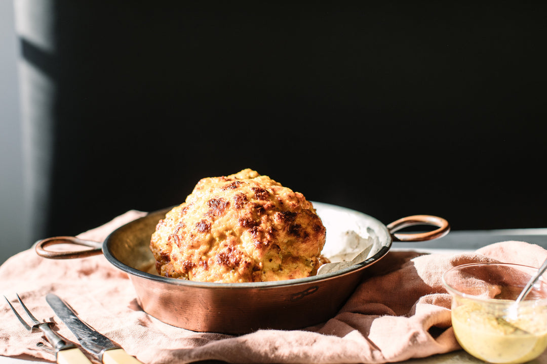 The Golden Dome of Cauliflower in a brass pan on a table with a side of Curry Dijon Mustard