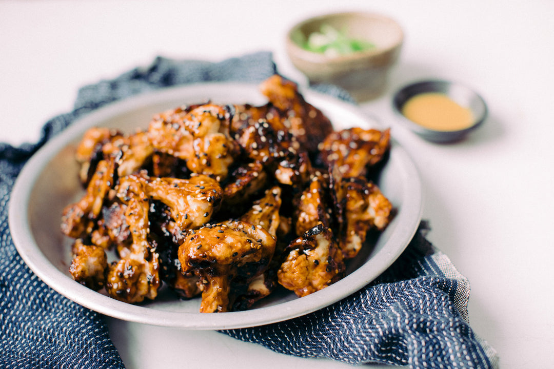 Spicy Sesame Cauliflower Wings in a white bowl set on a blue dish cloth