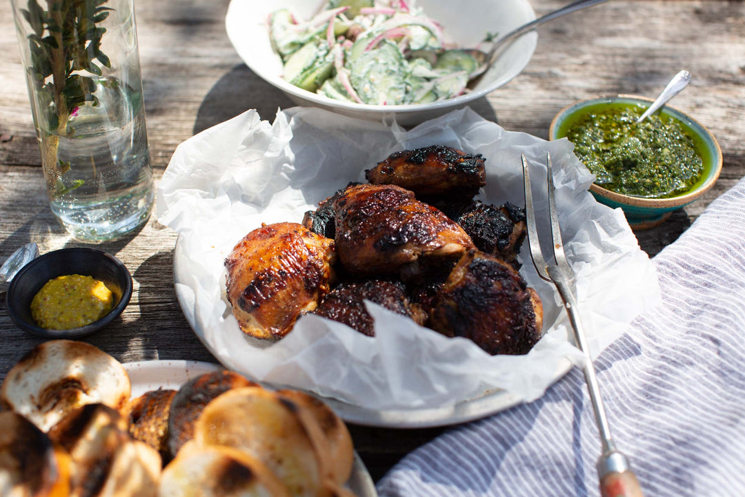 Curry Mustard Marinaded chicken on a picnic table with other summer dishes like a dill salad and naan bread