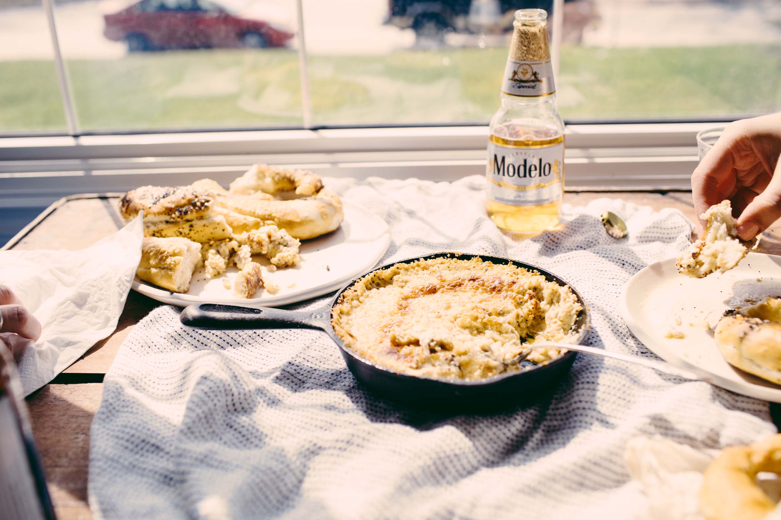 Oven Baked Warm Mustard Cheese Dip on a table with pretzels and beer being hit by direct sunlight